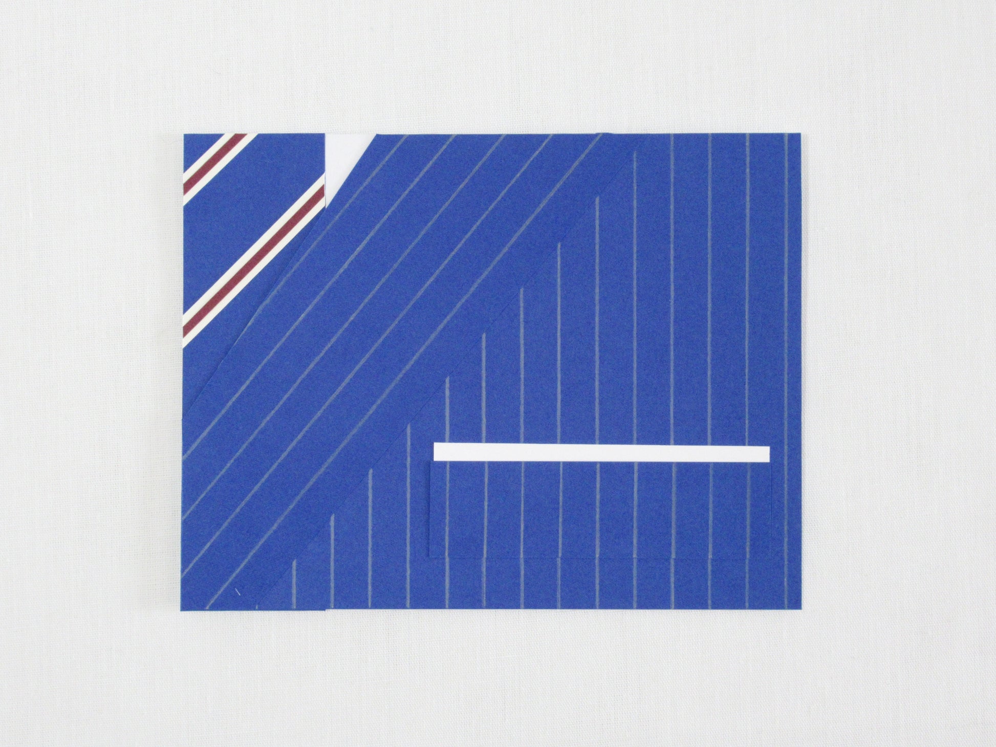 A card lays a white desk. The front of the card looks like a portion of person's suit, blue pinstripes, white pocket square, and a blue striped tie. It's designed to look like an outfit worn by Harry Hart in the movie Kingsman: The Secret Service.