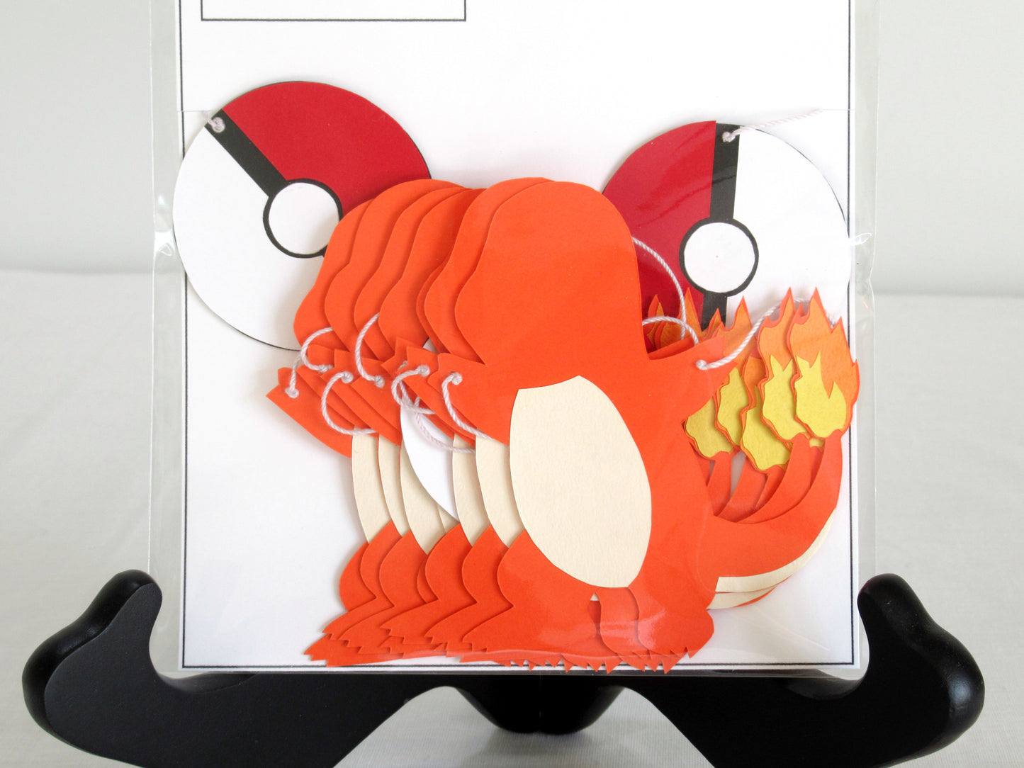 A close up of paper charmanders and pokeballs on a string inside a clear bag.