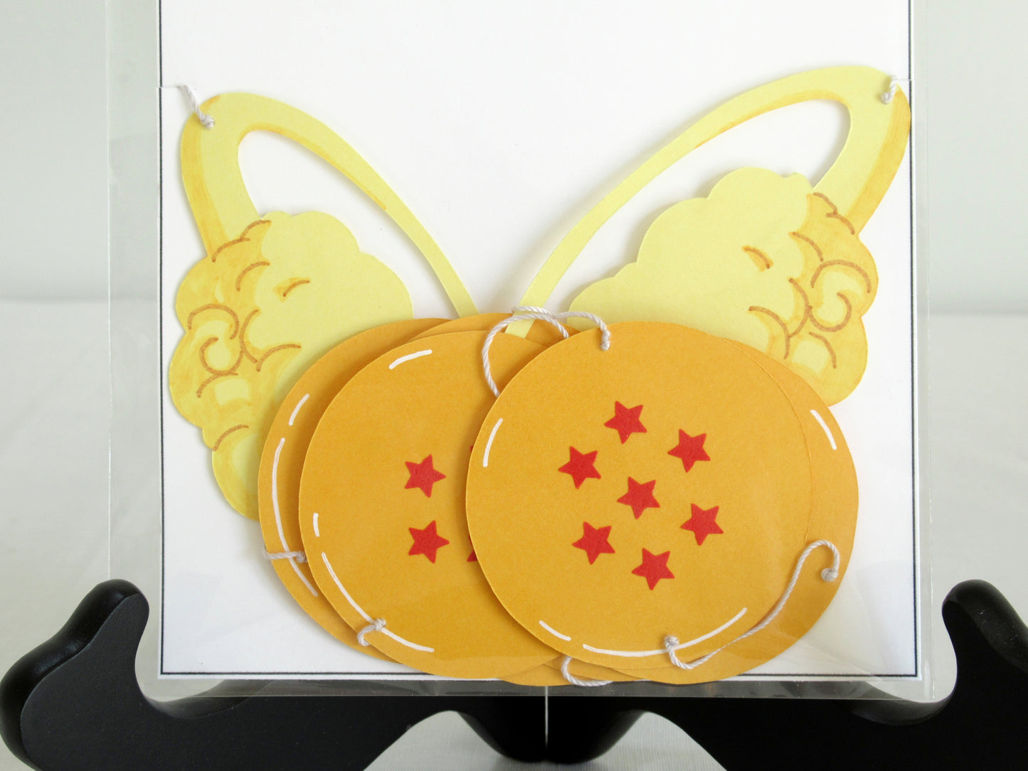 A close up of a garland with a series of paper dragon balls and nimbus arranged in neat bundle inside a clear bag.