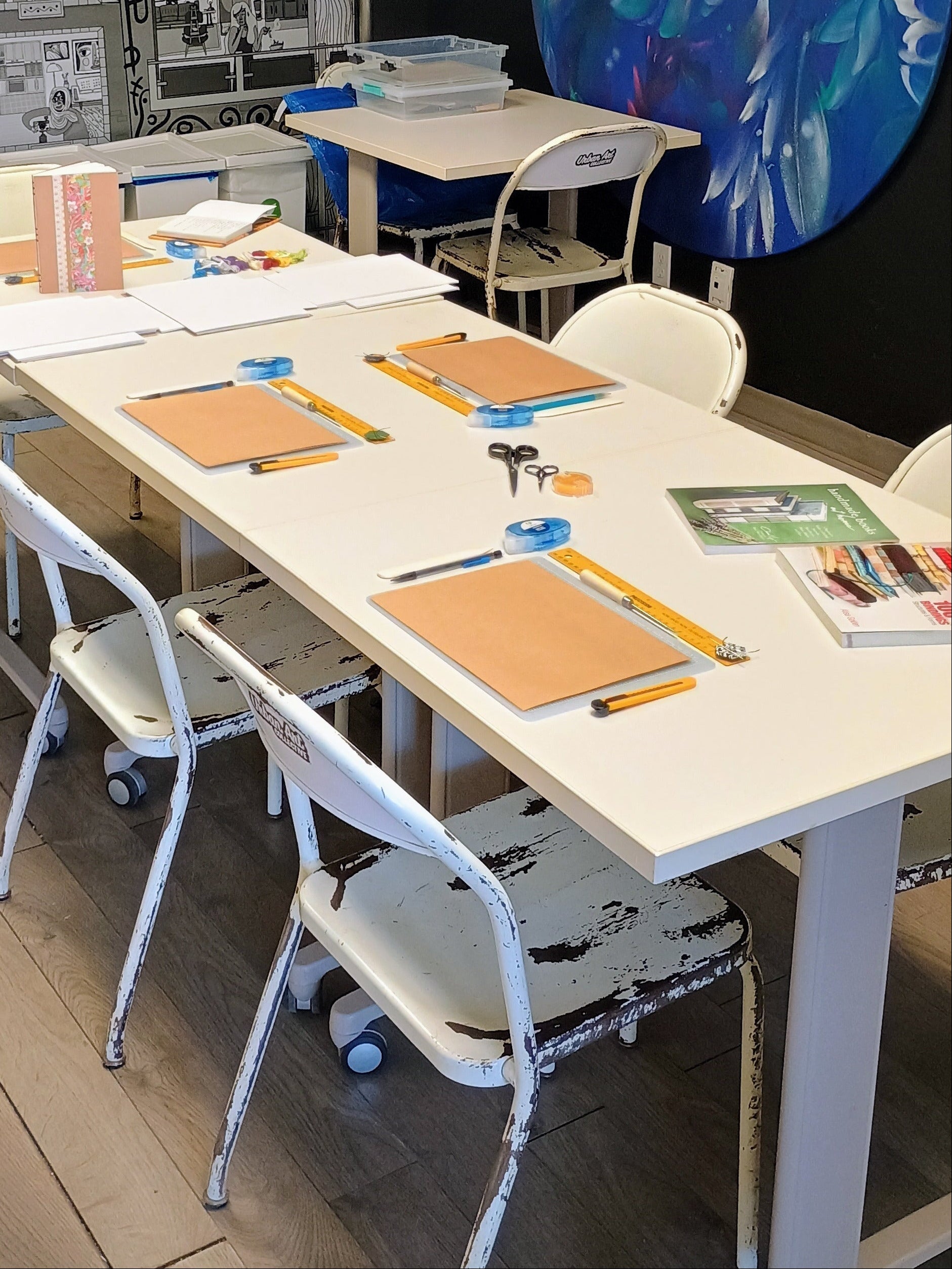 Classroom setup with tables, chairs, and bookbinding materials.