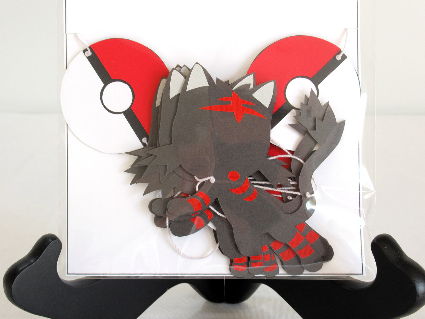 A close up of paper littens and pokeballs on a string inside a clear bag.