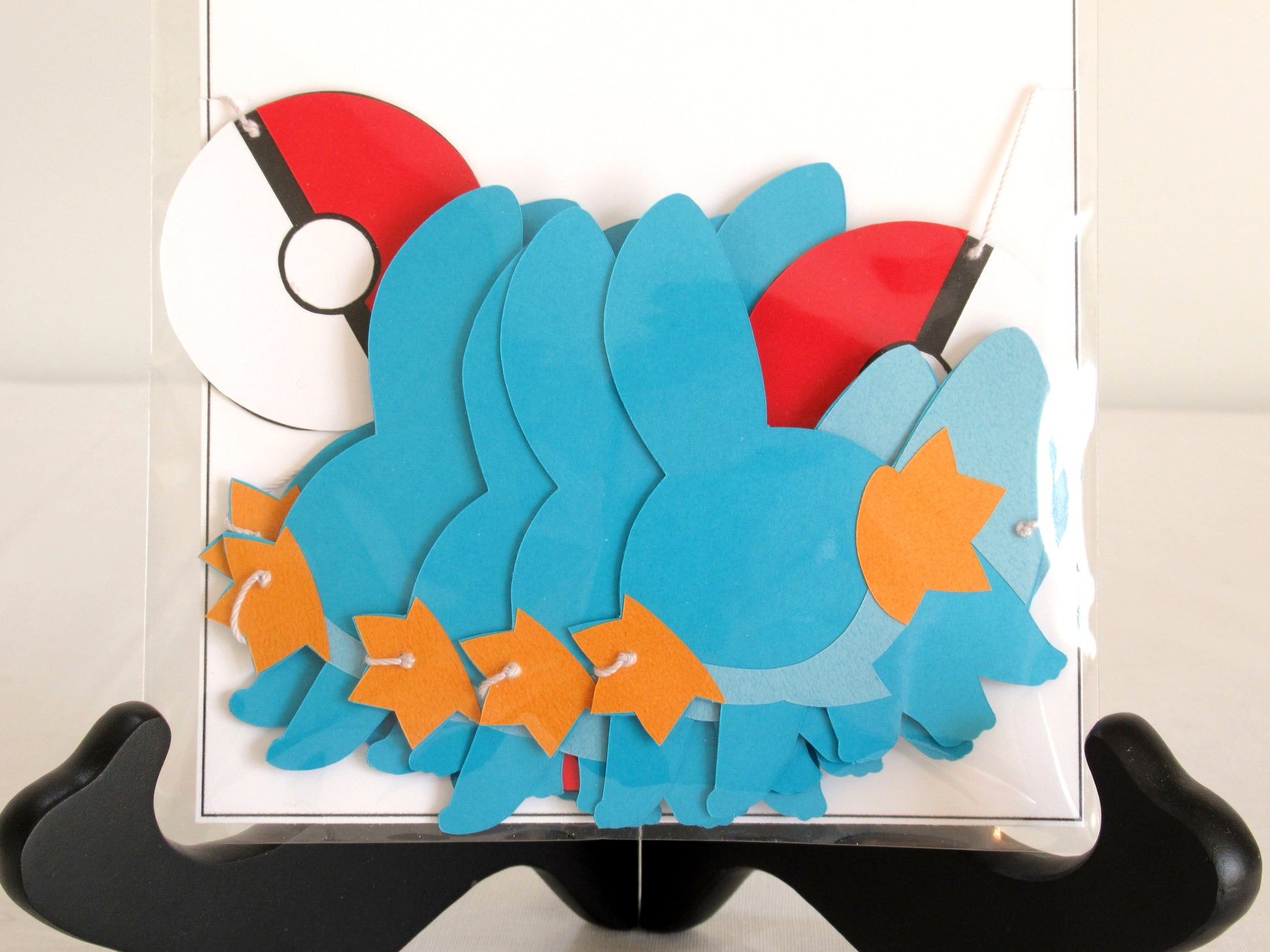 A close up of paper mudkips and pokeballs on a string inside a clear bag.