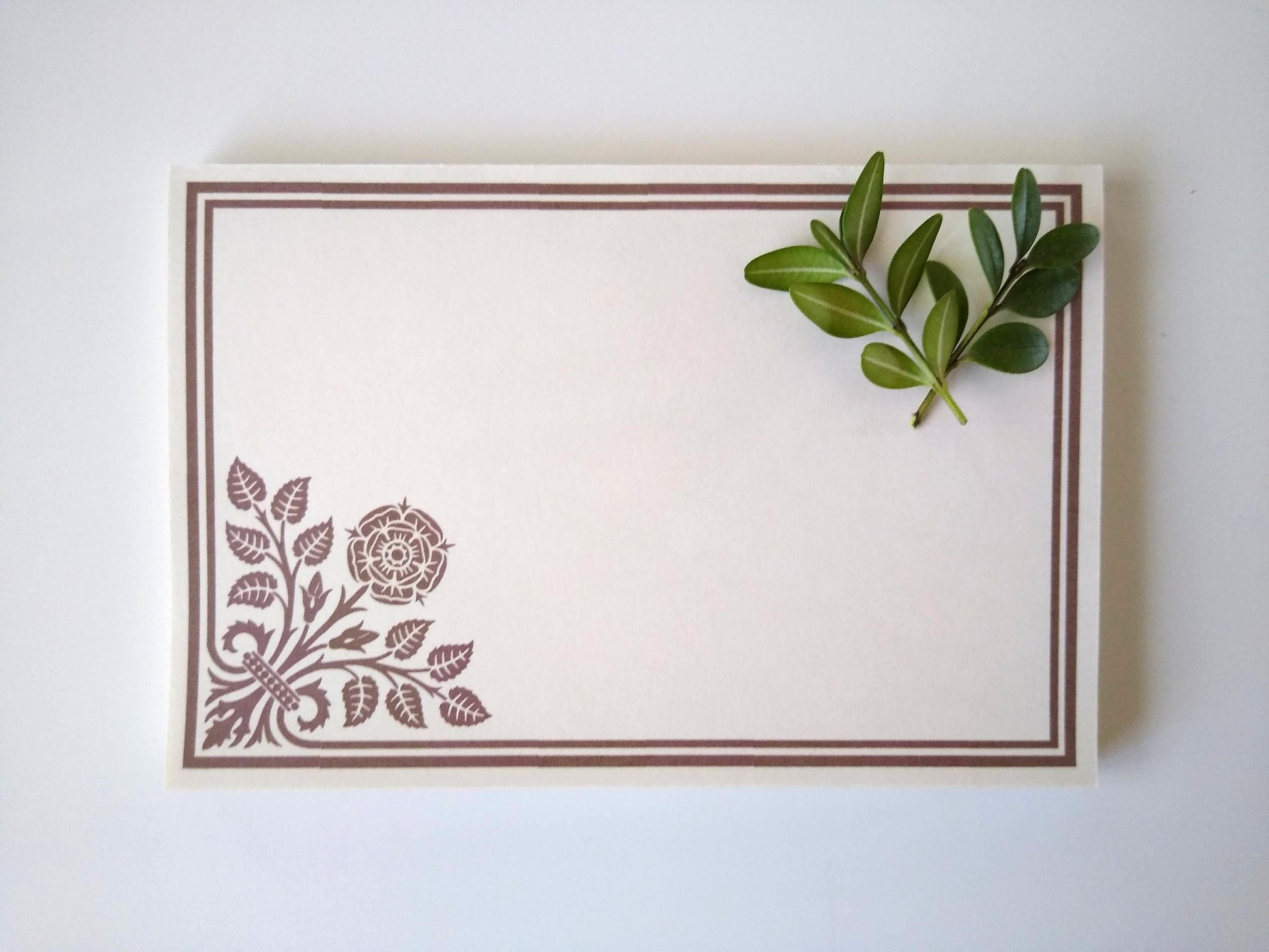 Single notepad with a stylized Peony design in the lower left corner. There is a double line border around the whole notepad. Two small sprigs of leaves rest on the upper right hand corner.